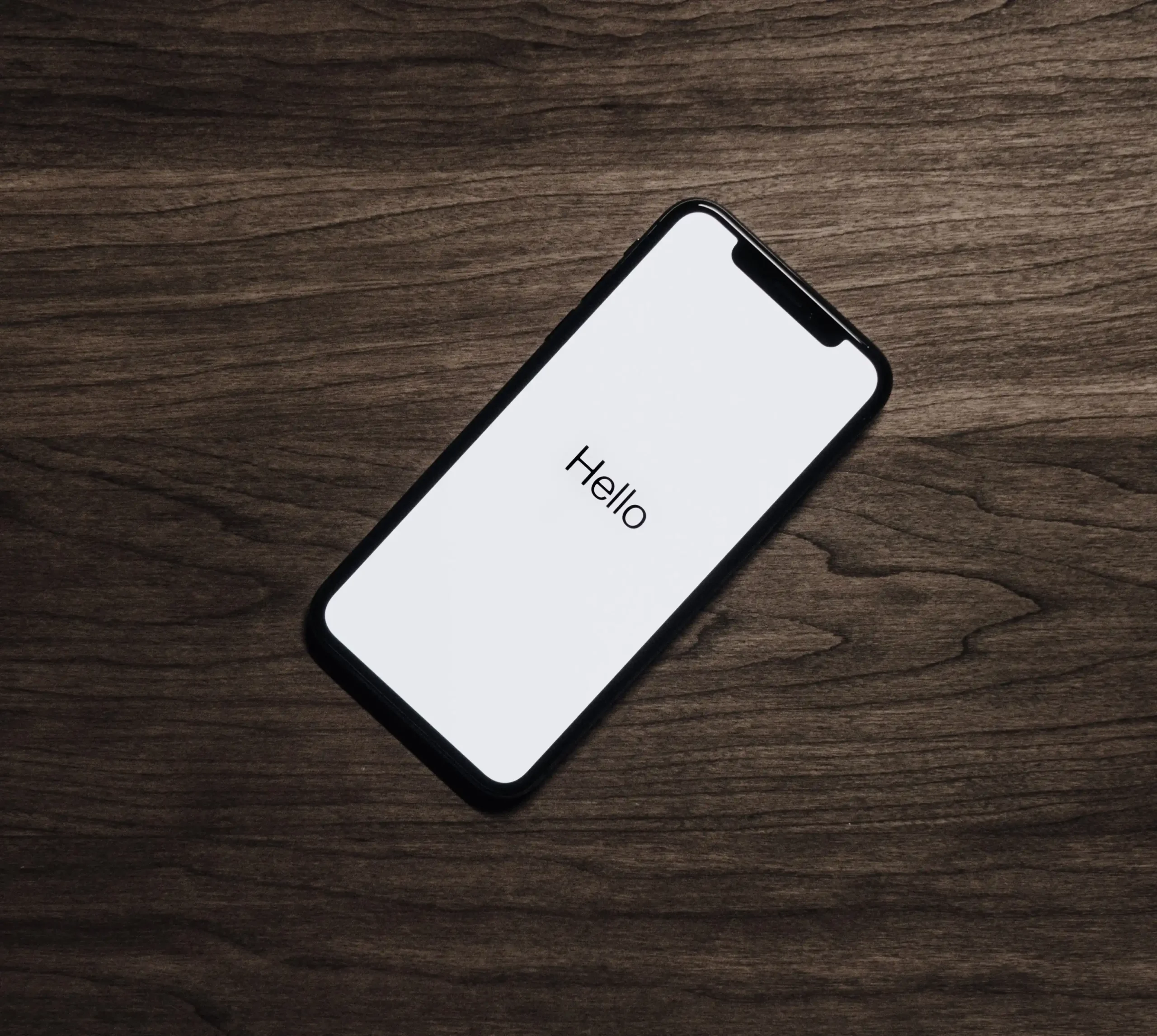 black-iphone-7-on-brown-table-699122 imagen iphone 11 con texto hola en el medio